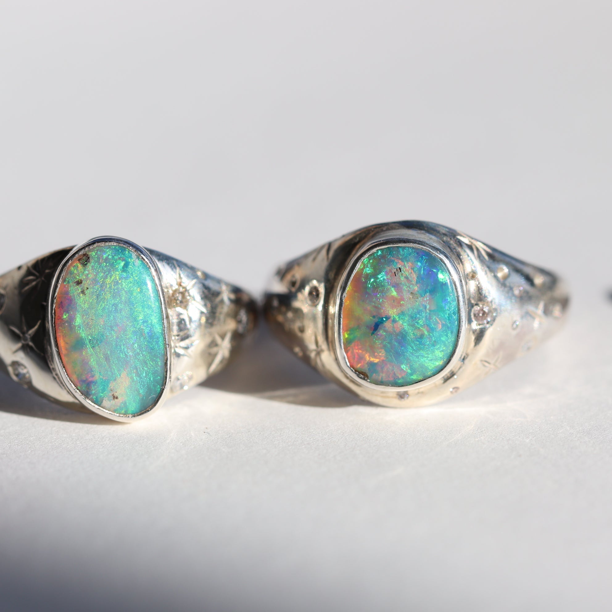 Two silver rings with opal stones on a white background