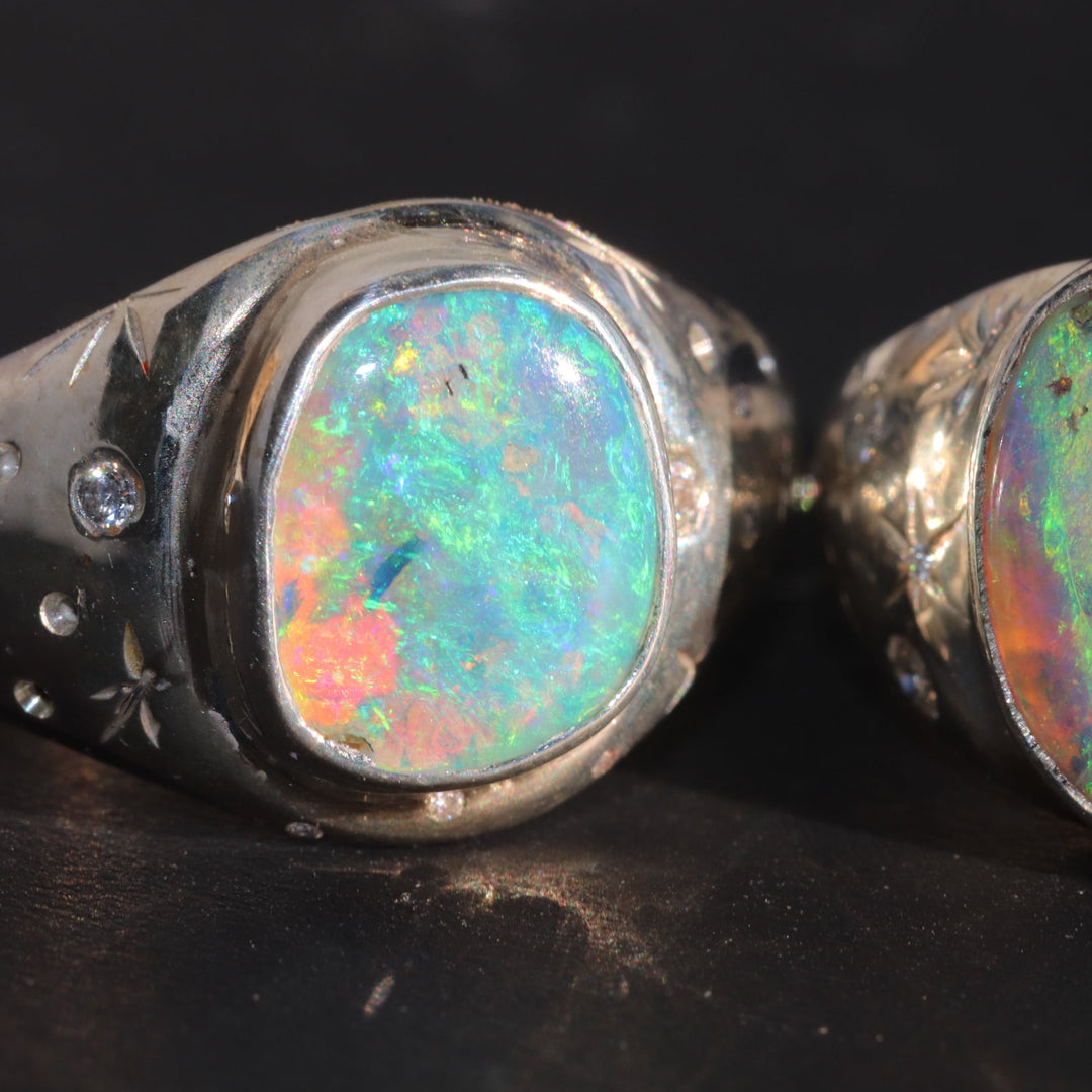 Two opal rings with silver settings on a dark background
